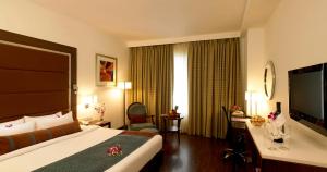 a hotel room with a bed and a large window at Royal Orchid Central, Pune in Pune