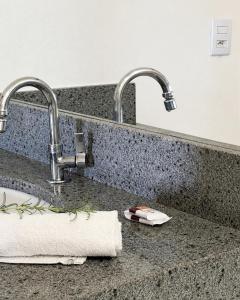 a sink with two faucets and a towel on a counter at Brisa do Lago Pousada in Capitólio +64 photos