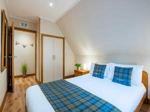 a bedroom with a large white bed with blue pillows at Chalet Glengarry Combi by Interhome in Spean Bridge