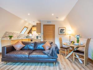 a living room with a leather couch and a table at Chalet Glengarry Combi by Interhome in Spean Bridge