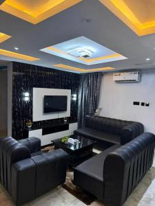 a living room with black leather furniture and a flat screen tv at Ofee Hotel and Suites in Nsukka
