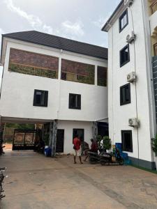 two people standing outside of a white building at Ofee Hotel and Suites in Nsukka