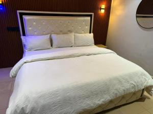 a large bed with white sheets and pillows at Ofee Hotel and Suites in Nsukka