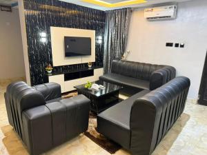 a living room with leather furniture and a flat screen tv at Ofee Hotel and Suites in Nsukka