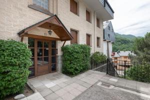 a house with a wooden door and a balcony at Apto Aloha Panticosa | Piscina | WIFI | Vistas in Panticosa