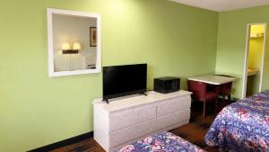 a room with a tv and a bed and a mirror at Seminole Inn in Donalsonville