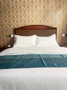 a bed with white sheets and a blue blanket at HH Inn in Lagos