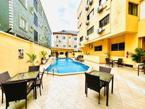 an apartment patio with a pool and tables and chairs at Presken Hotel Fajodd-4, Allen, Ikeja, Lagos in Ikeja