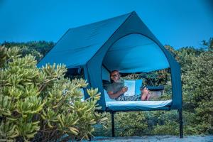 a man is sitting in a blue tent at Kuma Surf Camp in Arugam Bay