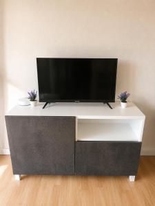 a white entertainment center with a flat screen tv on top at L'Élégant - 2 Voyageurs in Reims