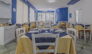 a dining room with tables and chairs with yellow tablecloths at Hotel ITALY in Misano Adriatico