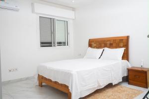 a white bedroom with a large bed and a window at residence madame sow in Dakar