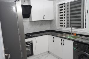 a small kitchen with white cabinets and a sink at residence madame sow in Dakar