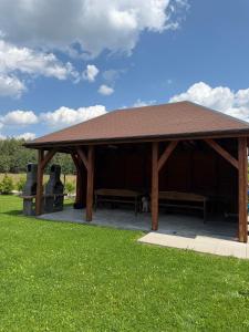 a wooden pavilion with two benches in a park at Agroturystyka Ostoja Wilków II in Wilków