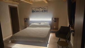 a bedroom with a white bed and a chair at Cabana Valea Brândușelor in Bran