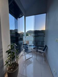 a balcony with two chairs and a plant at Chalés Aconchego in Cavalcante