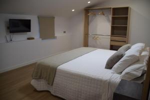 a bedroom with a white bed with a tv on the wall at Cortijo el Viznagar in Las Casicas