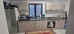 a kitchen with white cabinets and a sink and a microwave at Casa MIHNEA in Dălghiu