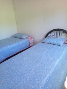 two twin beds in a bedroom with blue sheets at Aconchego Da Serra in Triunfo +2 photos