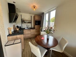 a kitchen with a wooden table and white chairs at Vida Bonita in Den Burg