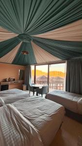 a bedroom with two beds and a table with a view at Wadi Rum Bella Rose Luxury Camp in Disah