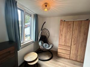 a room with a rattan swing in front of a window at Vida Bonita in Den Burg
