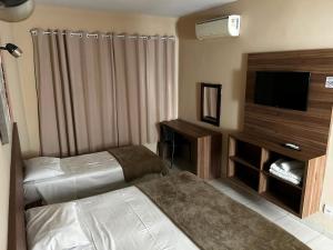 a hotel room with two beds and a flat screen tv at Espigão Palace Hotel in Resende