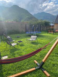 a group of chairs and a hammock in the grass at Sunny Side Cottage in Kazbegi