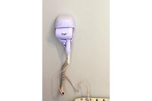 a white hairdryer hanging on a wall at Sam's Rooms in Vathí