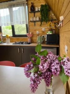 a vase of purple flowers on a table in a kitchen at Sunny Side Cottage in Kazbegi