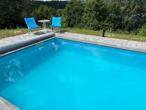 a swimming pool with two chairs and a table at Las,Jezioro,Masaże,SPA in Ostrzyce