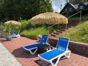 three lounge chairs and an umbrella on a brick patio at Las,Jezioro,Masaże,SPA in Ostrzyce