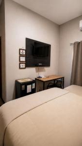 a hotel room with a bed and a flat screen tv at Hotel Miranda Maracaju in Maracaju