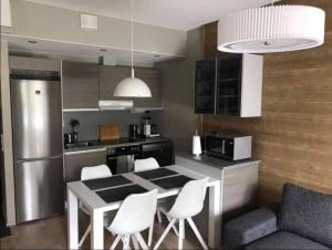 a kitchen with a table and some white chairs at Vierumäki Chalets 6 A4904 in Heinola