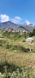 a field of grass with a town on top of a hill at Xinaliq Khinalig ELNUR GUEST HOUSE, New hotel in Xınalıq