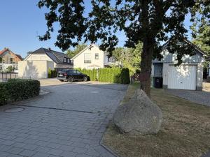 a rock sitting next to a tree in a driveway at Moderne Ferienwohnung über 2 Etagen in Bissendorf