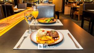 a table with a plate of food and a glass of orange juice at Edifício Praça Osório in Curitiba