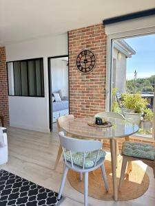 a dining room with a table and chairs and a brick wall at ROOF TOP 50m2 VUE MER !! à 2 mn à pied de la PLAGE et de la THALASSOTHERAPIE ! in Concarneau