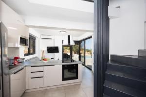 a kitchen with white cabinets and a view of a pool at Villa Andria in Apolpaina