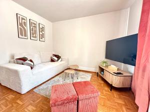 a living room with a white couch and a flat screen tv at La Parenthèse - Maison avec piscine privée in Wissembourg +16 photos