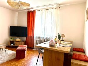 a living room with a table and chairs and a television at La Parenthèse - Maison avec piscine privée in Wissembourg