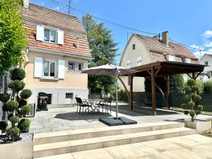 a patio with a table and an umbrella in front of a house at La Parenthèse - Maison avec piscine privée in Wissembourg