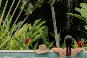 a woman sitting in a swimming pool looking at plants at Casas Versos do Mar in Marau