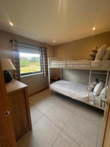 a bedroom with two bunk beds and a window at Sputieburn Bothy in Brora