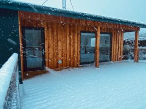 a log cabin in the snow with snow covered ground at Sputieburn Bothy in Brora