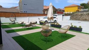 a group of chairs and an umbrella on a lawn at Apartamentos PRAIA DO CANSORRO in Camariñas