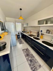 a large kitchen with white counters and a refrigerator at ROOF TOP 50m2 VUE MER !! à 2 mn à pied de la PLAGE et de la THALASSOTHERAPIE ! in Concarneau