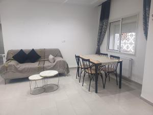 a living room with a couch and a table and chairs at Studio en rez-de-chaussée in Hammamet