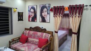 a living room with a couch and pictures on the wall at Swapna-Nir in Howrah