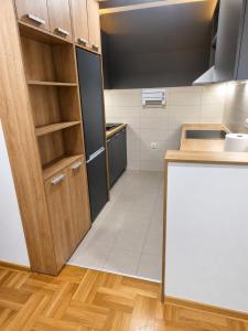 a kitchen with a black refrigerator and wooden cabinets at Lux apartman Ub II in Ub